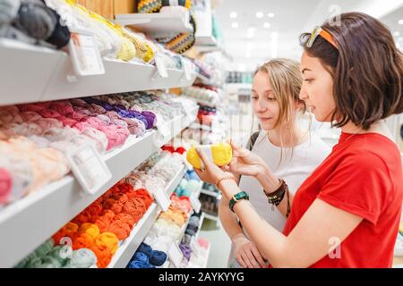 Woman choosing yarn and wool balls for purchase in craft shop Stockfoto