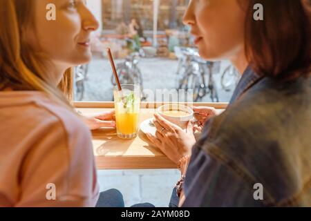 Zwei glückliche Mädchen, die in einem Café zu Mittag essen, Kaffee trinken und reden. Freundschafts- und Lifestyle-Konzept Stockfoto