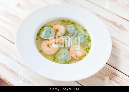 Suppenklöße und Garnelen werden mit Lauch serviert. Auf altem weißen Holzhintergrund. Stockfoto