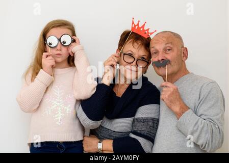 Urlaub. Schöne Family-Alt-Mann Frauen und Kleines Lustiges Mädchen In Masken, Die Purim, Neujahr, Weihnachten, Geburtstag feiern. Porträt Glücklicher Menschen In Festlichen Karnevalsmasken Mit Spaß Bei Party. Stockfoto