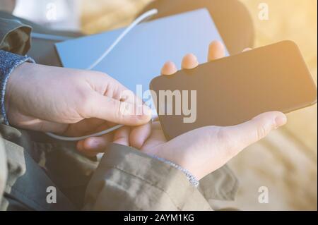 Frau hält den schwarzen Smartphone-Ladeakku von einer externen Strombank Stockfoto