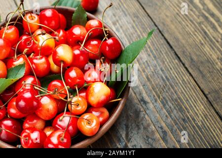 Frische Ernte von Süßkirschen in einer Tonschale auf einem Holztisch. Gesunde Früchte. Stockfoto