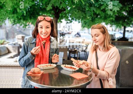 Zwei Mädchen-Freunde Studenten essen Currywurst fast Food Deutsch Gericht Schweinewurst im Outdoor-Street-Food-Café Stockfoto