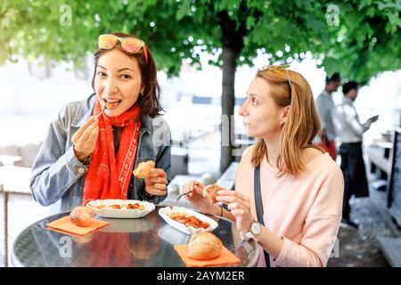 Zwei Mädchen-Freunde Studenten essen Currywurst fast Food Deutsch Gericht Schweinewurst im Outdoor-Street-Food-Café Stockfoto