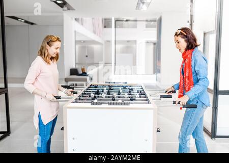 Zwei Mädchen Freunde spielen Tischfußball Minispiel drinnen Stockfoto