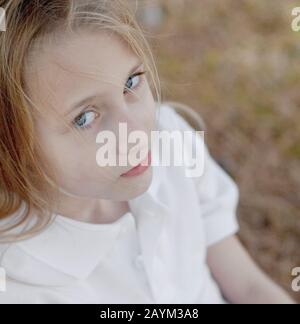 Ein introspektives, hübsches junges Mädchen mit blonden Haaren und blauen Augen. Stockfoto