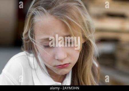 Ein trauriges Mädchen mit blondem Haar, das nach unten blickt. Stockfoto