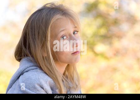 Ein hübsches junges Mädchen mit blauen Augen und blonden Haaren mit grauem Hoodie. Stockfoto