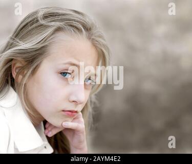 Ein introspektives, hübsches junges Mädchen mit blonden Haaren und blauen Augen. Stockfoto