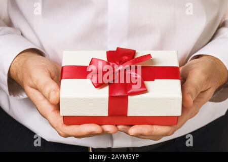 Ein Mann mit einem Geschenk in den Händen aus der Nähe. Urlaubskonzept Stockfoto