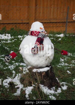 Ein Schneemann auf einem Baumstumpf im schmelzenden Schnee Stockfoto