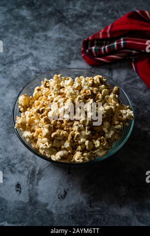 Caramel Popcorn in Glasküssel auf grauer Oberfläche für Snack. Stockfoto