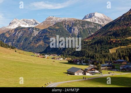 Zwei Touristen mit dem Fahrrad, die sich dem Dorf Zug im sonnigen Lechtal nähern, Lech, Arlberg, Österreich Stockfoto