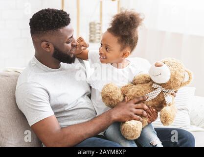 Afro kleine Tochter kuschelt mit ihrem Papa, während sie zusammen spielt Stockfoto