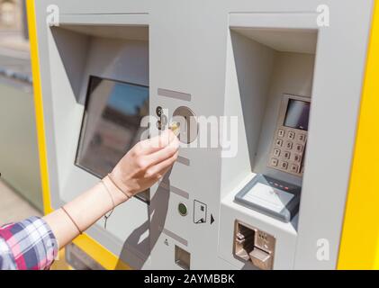 Junge Frau zahlt am Fahrkartenautomaten in einem öffentlichen Verkehrsbahnhof Stockfoto