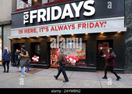 Menschen, die an einem TGI Fridays Happy Hour Themen-Kettenrestaurant in der 604 5th Ave in Midtown Manhattan, New York, New York, New York vorbeilaufen. Stockfoto