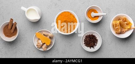 Curcuma-Wurzel, Zimt, Ingwer, Milch auf konkretem Hintergrund Stockfoto