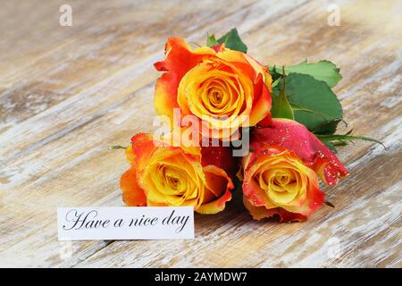 Haben Sie eine schöne Tageskarte mit drei orangefarbenen Rosen, die mit Glitter auf Holzoberfläche bedeckt sind Stockfoto