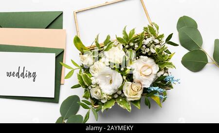 Komposition goldener Hochzeitsringe auf schönen weißen Rosen Stockfoto