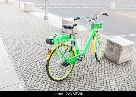 Modernes grünes Elektrofahrrad, das auf dem Bürgersteig in der Stadt abgestellt ist Stockfoto