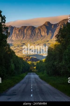 Die Bergkette des Knockan Crag National Nature Reserve bei Sonnenuntergang, von der zweispurigen Autobahn A385 in der Nähe von Elphin, Lairg, Schottland aus gesehen. Stockfoto