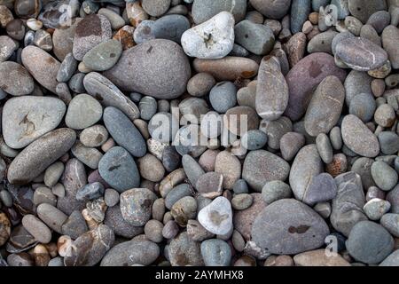 Meer Kieselsteinen farbige Granit am Strand Hintergrund Steine. Der Strand mit Sand und Steine von den Wellen des Meeres umspült. Stockfoto