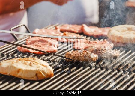 Der Küchenchef kocht auf der Straße und bereitet Hackschnitzel und Brot auf dem Grill für Hamburger zu Stockfoto