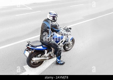 Rückansicht des nicht erkennbaren Motorradfahrers mit Hightech-Schutzanzug beim Fahren eines Moder-Sport-Motorrads Stockfoto