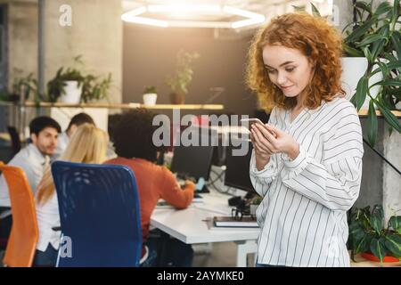 Hübsches junges Mädchen, das während des Arbeitstages mit dem Handy telefoniert Stockfoto