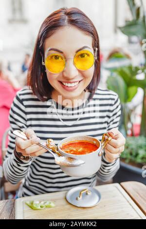 Eine Frau isst in einem Restaurant im Freien eine traditionelle ungarische Gulasch- oder Tomatensuppe aus einem Topf Stockfoto