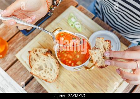 Eine Frau isst in einem Restaurant im Freien eine traditionelle ungarische Gulasch- oder Tomatensuppe aus einem Topf Stockfoto