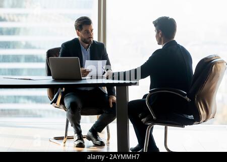 Seriöse Unternehmer im Anzug, die den lebenslauf halten, um neuen Kandidaten anzuhören. Stockfoto