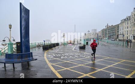 Brighton UK 16. Februar 2020 - EIN Läufer brettert das Wetter an der Küste von Brighton, als Storm Dennis den Großteil Großbritanniens heute mit starkem Regen und starken Gale Force Winden beschert: Credit Simon Dack / Alamy Live News Stockfoto