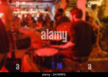 Drummer, der auf Drum-Set im Nachtjazzclub im Freien spielt, verschwommener abstrakter Musikhintergrund Stockfoto