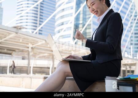 Geschäftserfolg - Fröhliche Gesten asiatischer Wirtschaftsfrauen in der Stadt. Stockfoto