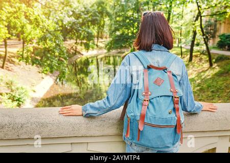 Junge hübsche brünette Frau, die im Park in Budapest unterwegs ist und auf einer Brücke über den alten Kanal steht Stockfoto