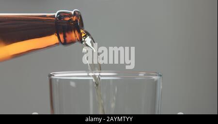 Bier aus brauner Flasche in Glas gießen, breites Foto Stockfoto