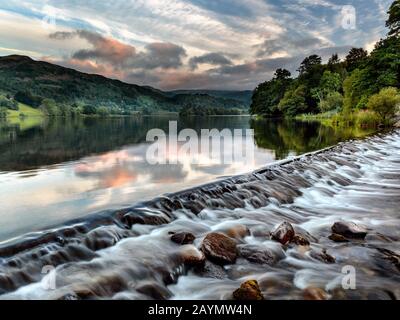 Das Wasser fließt über das Wehr am Grasmere Lake. Der Fluss Rothay verlässt den Grasmere Lake in Richtung Rydal. Lake District, Cumbria, England, Großbritannien Stockfoto