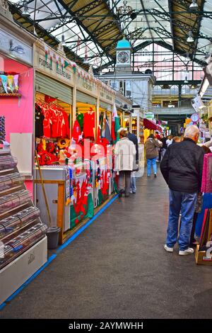 Kunden des KC Sports Stalls, die eine bunte Auswahl an walisischen Sportartikeln verkaufen. Cardiff Central Indoor-Markt, eröffnet im Jahr 1891. Stockfoto