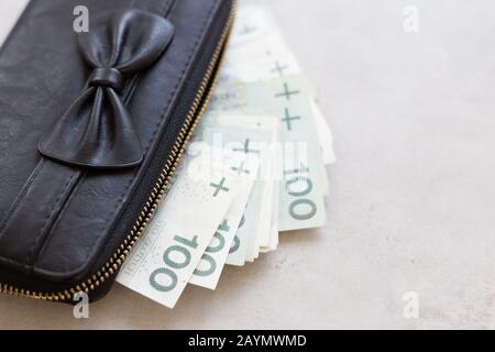Reiche Mädchen oder Frauen in Polen. Schwarze Geldbörse voller polnischem Geld auf grauem Marmortisch Stockfoto