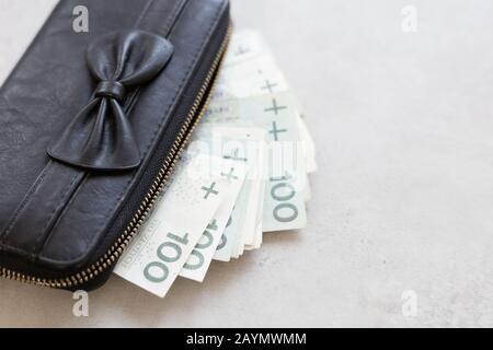 Reiche Mädchen oder Frauen in Polen. Schwarzer Geldbeutel voll polnischem Geld auf dem Tisch Stockfoto