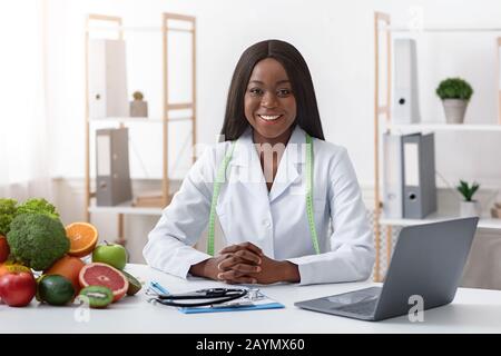 Lächelnder Ernährungsberater mit Gemüse und Obst im Büro Stockfoto