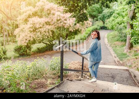 Im Stadtpark spaziert das Mädchen von Hipper auf dem Weg und schaut im Frühjahr auf die blühenden Bäume Stockfoto