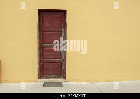 Verwitterte, geschlossene alte rote Tür in gelber Wand, La Palma, Kanarische Inseln, Spanien Stockfoto