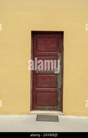 Verwitterte, geschlossene alte rote Tür in gelber Wand, La Palma, Kanarische Inseln, Spanien Stockfoto