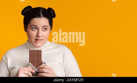 Portrait Von Pensivem Adipösen Mädchen Mit Chocolate Bar In Den Händen Stockfoto