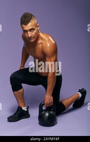 Gutaussehender, müder Kerl, der nach dem effektiven Workout eine Pause hat, mit Blick auf die Kamera. Foto in voller Länge. Isolierter blauer Hintergrund, Studioaufnahme. Entspannung, Stockfoto