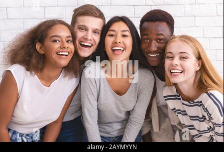 Porträt glücklicher multiethnischer junger Freunde über weißem Wandhintergrund Stockfoto