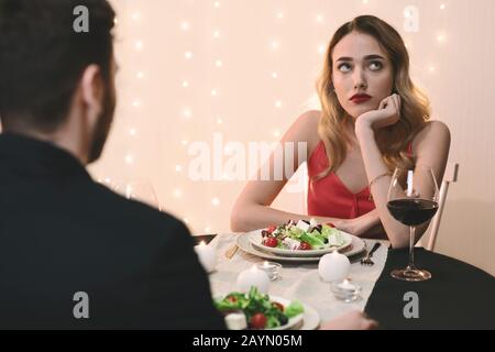 Junge Frau beim romantischen Abendessen im Restaurant gelangweilt Stockfoto