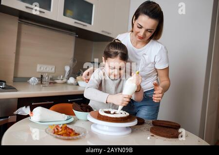 Mummys Helfer: Kinder- und hier-Mutter genießen Freude am Kochen. Hausaufgaben, Freundschaft, Teamarbeit, Geschenk für Papa Stockfoto